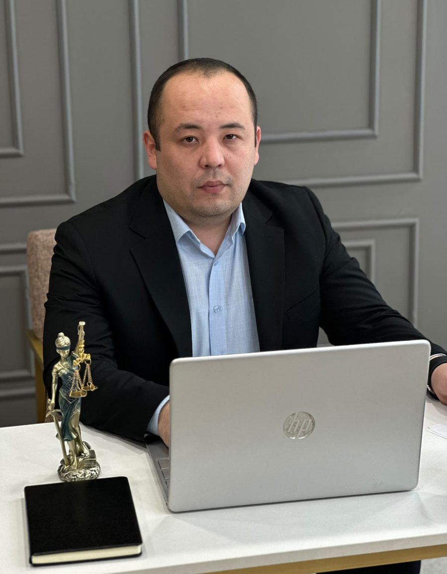 Юрист Фараби Тузелов за рабочим столом со статуэткой Фемиды